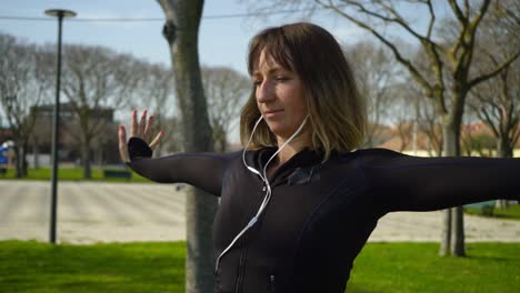 Focused-sporty-girl-in-earphones-exercising-in-park
